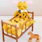 A Roommate toy sat on top of the Roommate Doll Bedding Set - Tiger, which is inside a wooden baby bed