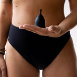 A person holding the Black Silicone, BPA free and latex free Ruby Cup in the palm on their hand