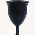 Ruby Cup Menstrual Cup in black silicone, on a cream background