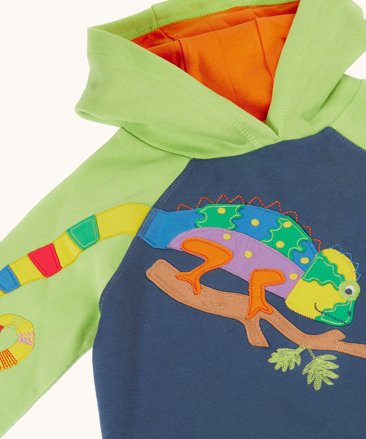 A close up of the chameleon applique on the front of the Frugi children's organic cotton hoodie. The multi coloured chameleon applique is placed on the chest with it's tail on the arm of the hoodie.