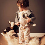 A child stood on a Wobbel board with a sheep skin like rug, holding the Senger Baby Cat