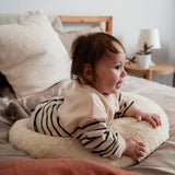 A baby lying on top of the Senger nursing and neck soft warm cushion showing scale. Cushion available at Babipur. 