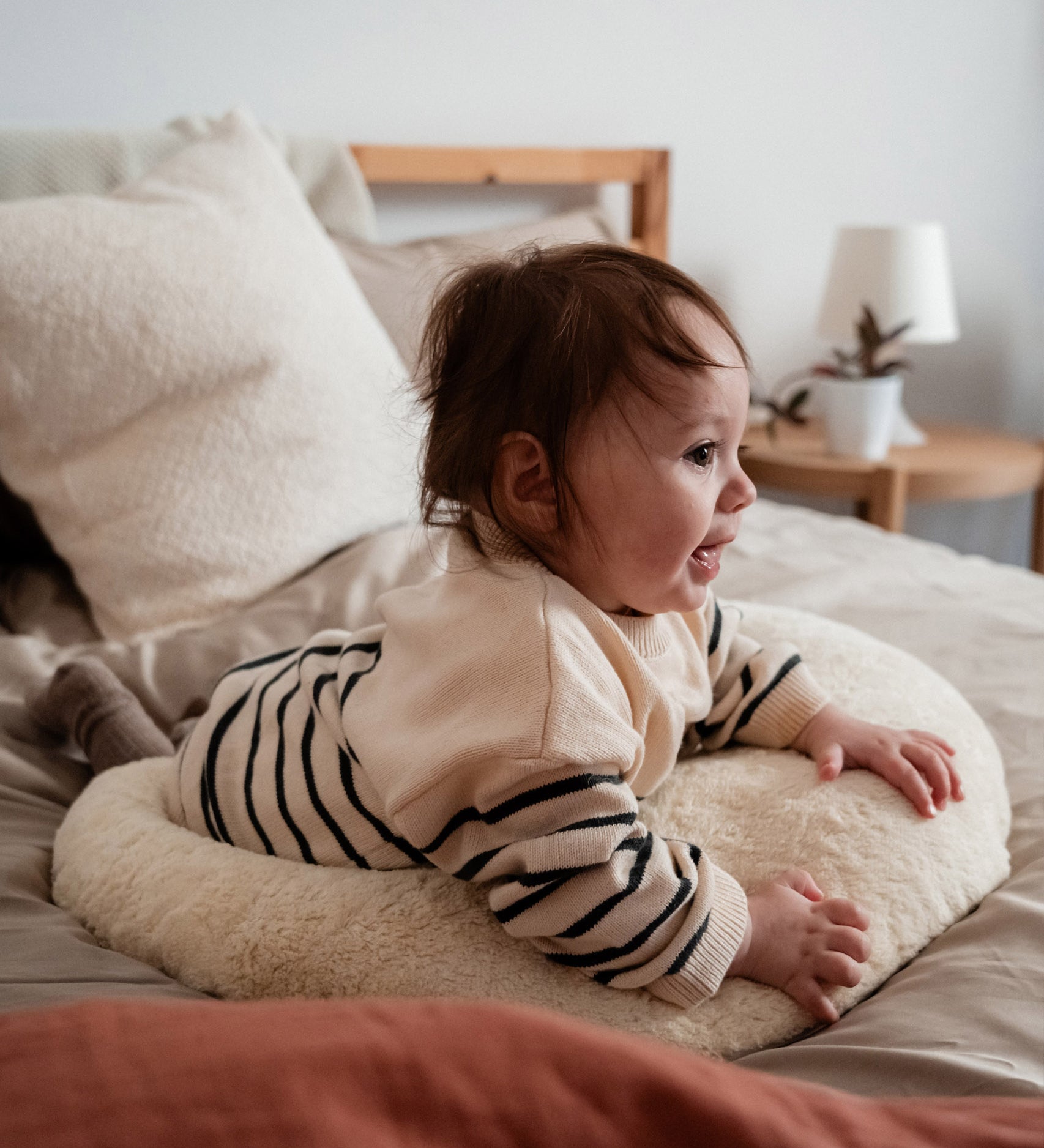 A baby lying on top of the Senger nursing and neck soft warm cushion showing scale. Cushion available at Babipur. 