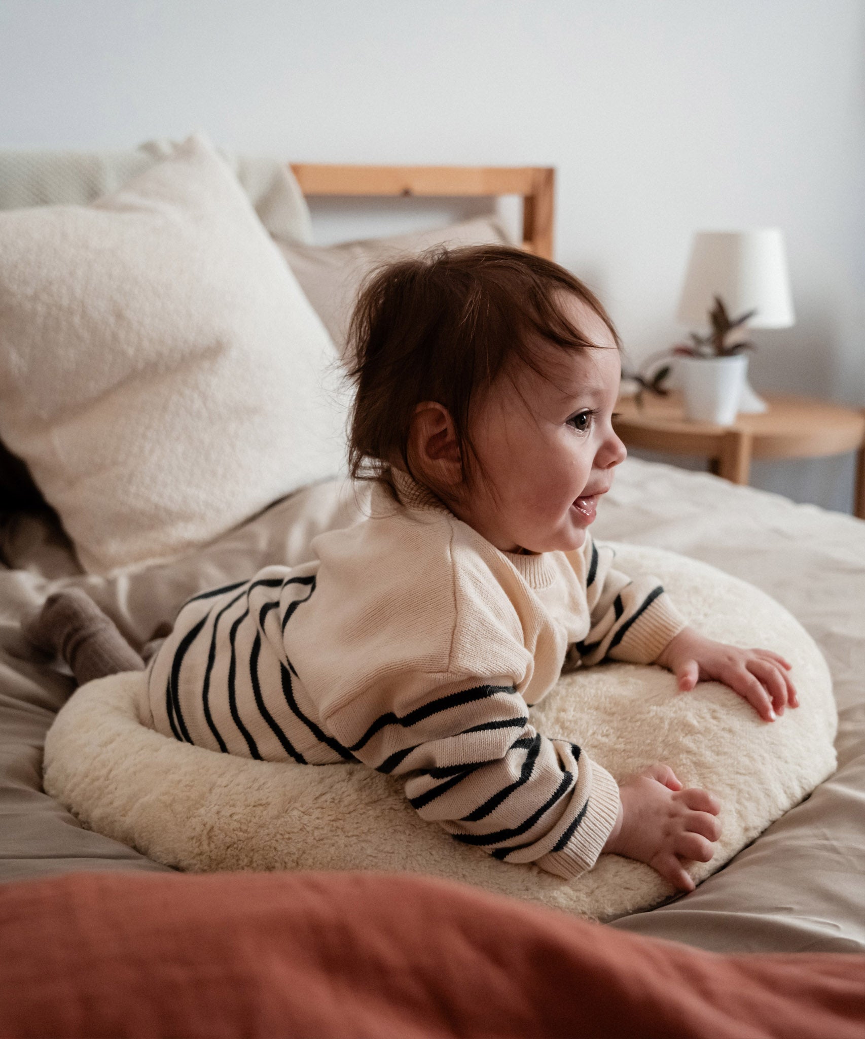 A baby lying on top of the Senger nursing and neck soft warm cushion showing scale. Cushion available at Babipur. 