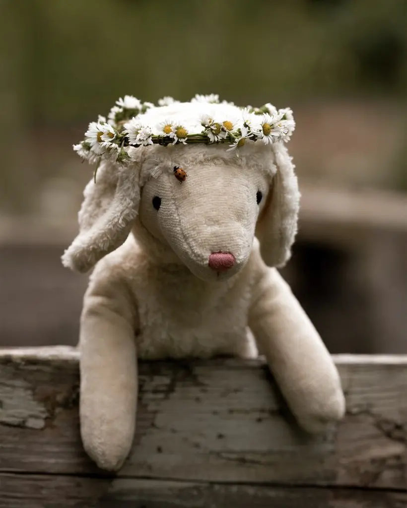 Senger Floppy White Sheep soft toy in size small, made from organic cotton filled with wool, outside wearing a flower crown.