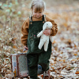 Senger White Sheep, made from organic cotton and wool, a small floppy soft toy, held by child in forest.