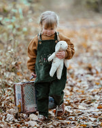 Senger White Sheep, made from organic cotton and wool, a small floppy soft toy, held by child in forest.