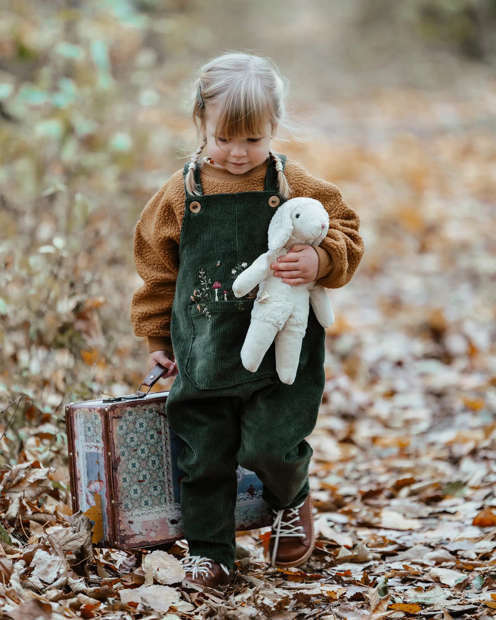 Senger White Sheep, made from organic cotton and wool, a small floppy soft toy, held by child in forest.