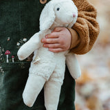 Senger White Sheep, a small floppy soft toy made from organic cotton and wool, in child's arm.