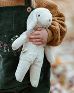 Senger White Sheep, a small floppy soft toy made from organic cotton and wool, in child's arm.