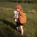 Senger Floppy White Sheep toy, made from organic cotton filled with wool, held by child walking in a field.