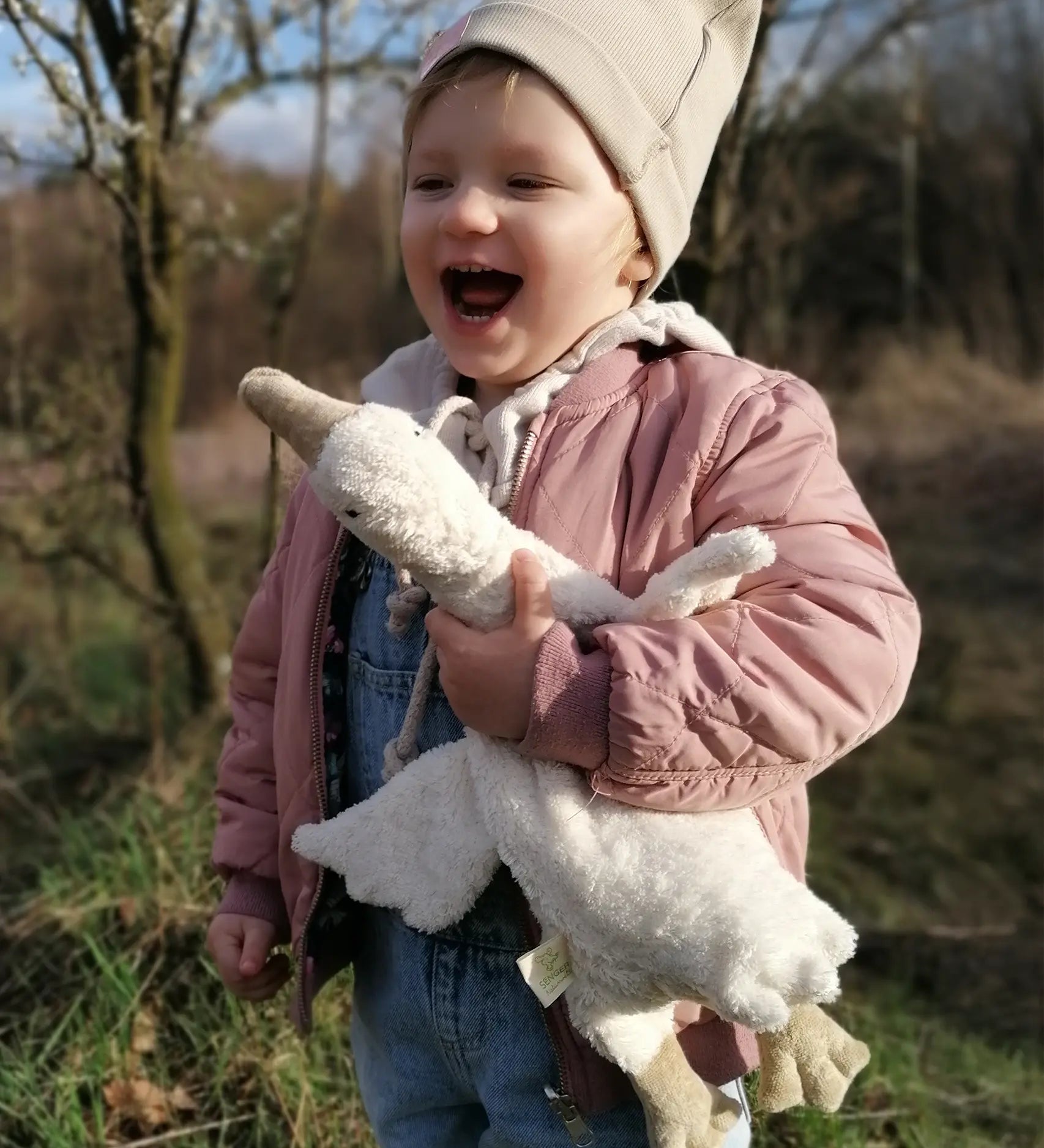 Senger naturwelt white small goose toy, made from organic cotton, held by child.
