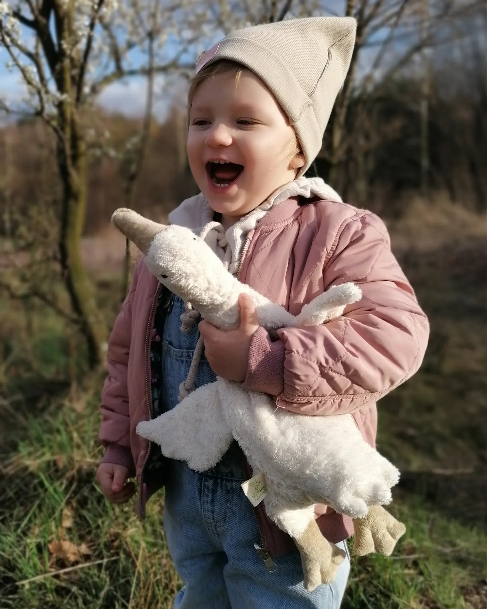 Senger naturwelt white small goose toy, made from organic cotton, held by child.