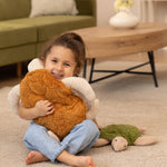 A child is smiling happily and is holding a larger Senger Cuddly Turtle with a brown shell. The Small Cuddly Turtle is next to the child