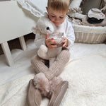 A child at on the floor in their room, holding the Senger Large Cuddly Polarbear and a cup of hot chocolate in their hand