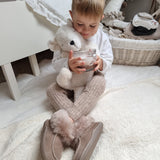 A child at on the floor in their room, holding the Senger Large Cuddly Polarbear and a cup of hot chocolate in their hand