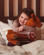 Senger Naturwelt Large Cuddly Deer Organic Soft Toy, made from wool and organic cotton, held by child on bed.