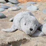 Senger Naturwelt Large Cuddly Grey Seal Organic Soft Toy, made from cotton and filled with spelt chaff, on a beach.