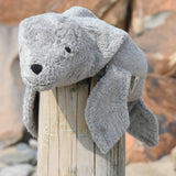 Senger Naturwelt Small Cuddly Grey Seal Organic Soft Toy, made from wool and organic cotton on a log at the beach.