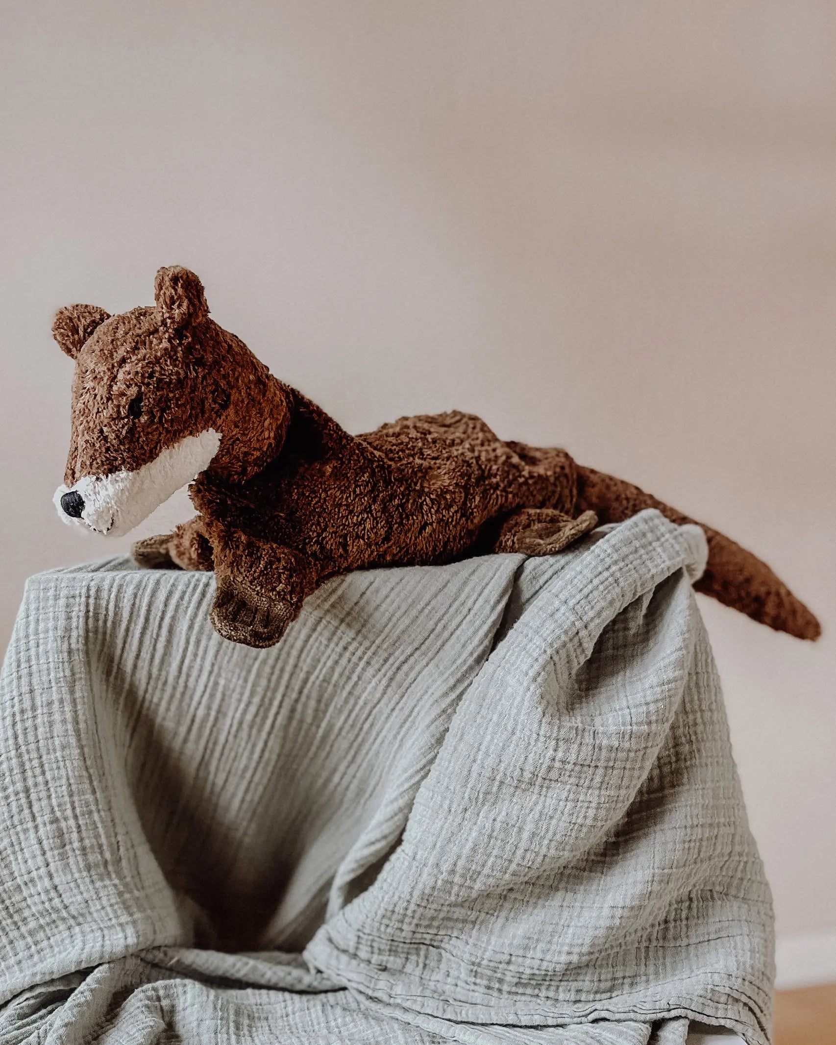 Senger Naturwelt seal, a small brown cuddly soft toy made from natural materials, on a grey muslin blanket.