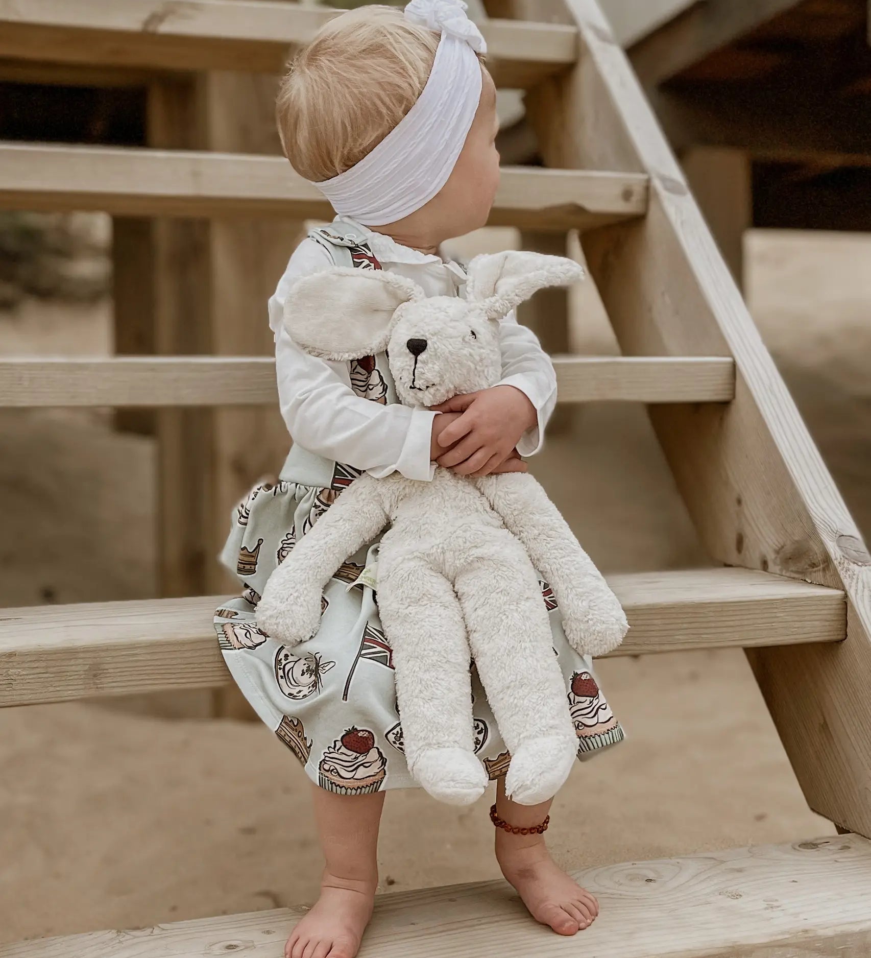 Senger Naturwelt Floppy White Rabbit Size Large, made from organic materials, held by child on a beach.
