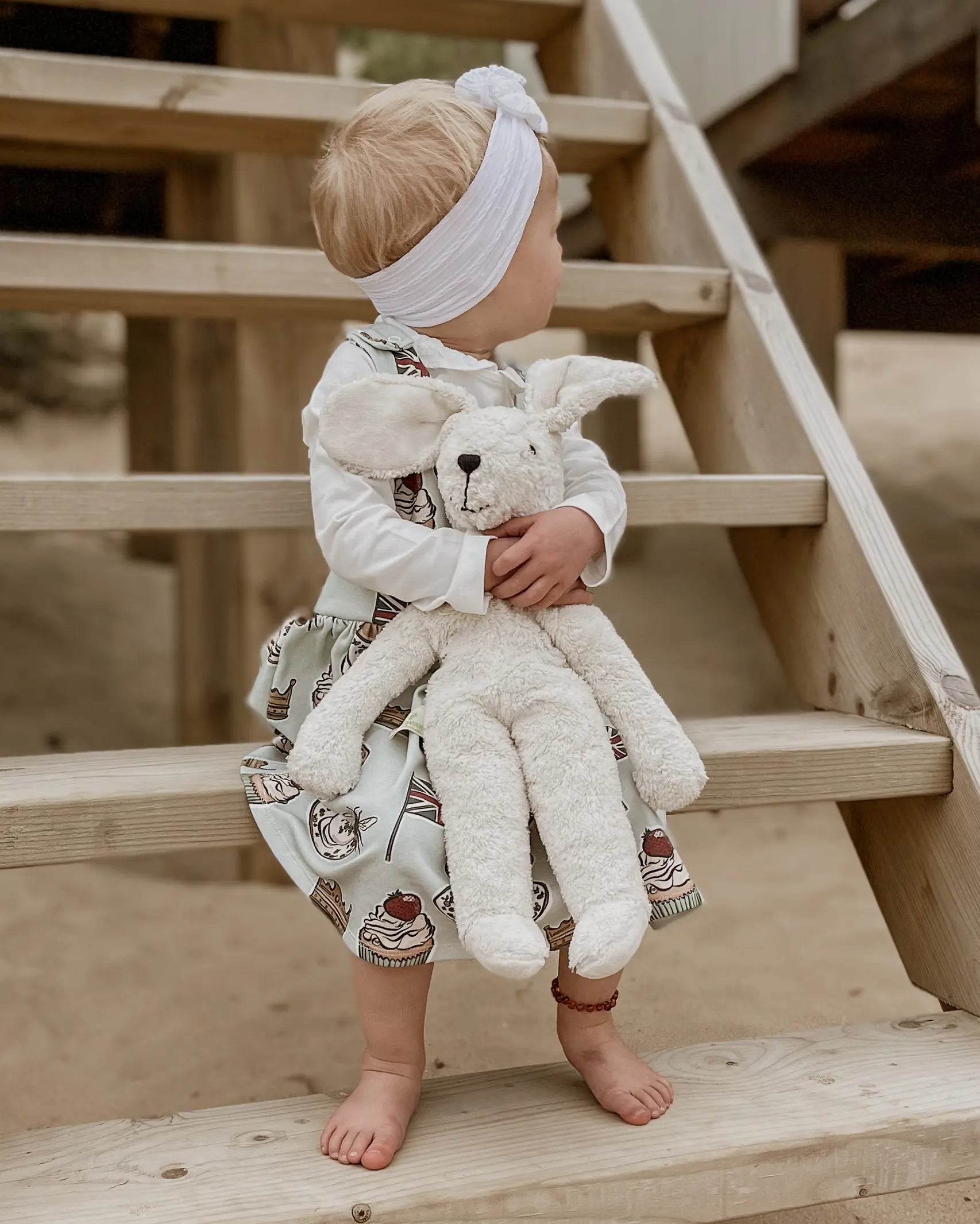 Senger Naturwelt Floppy White Rabbit Size Large, made from organic materials, held by child on a beach.