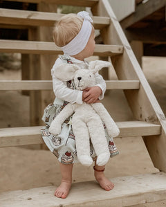 Senger Naturwelt Floppy White Rabbit Size Large, made from organic materials, held by child on a beach.
