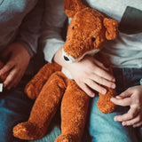 Senger Naturwelt Large Floppy Fox orange soft toy, made from organic cotton, on child's lap.