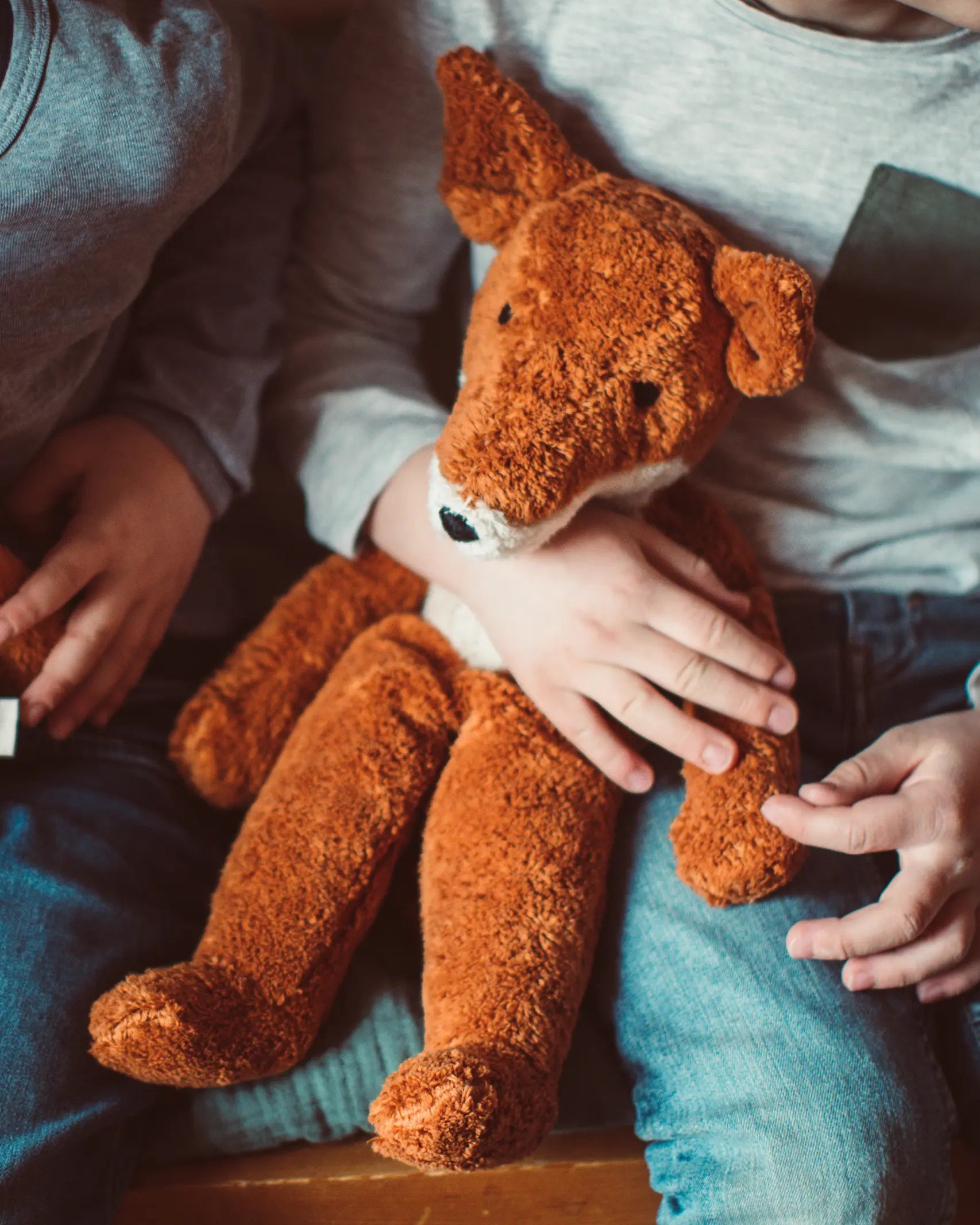 Senger Naturwelt Large Floppy Fox orange soft toy, made from organic cotton, on child's lap.