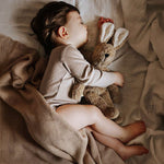 A child sleeping, cuddling the Senger Small Floppy Beige Rabbit