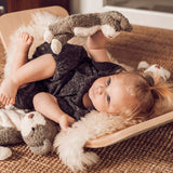 A child laying down in a Wobbel board, playing with a Senger Baby Cat
