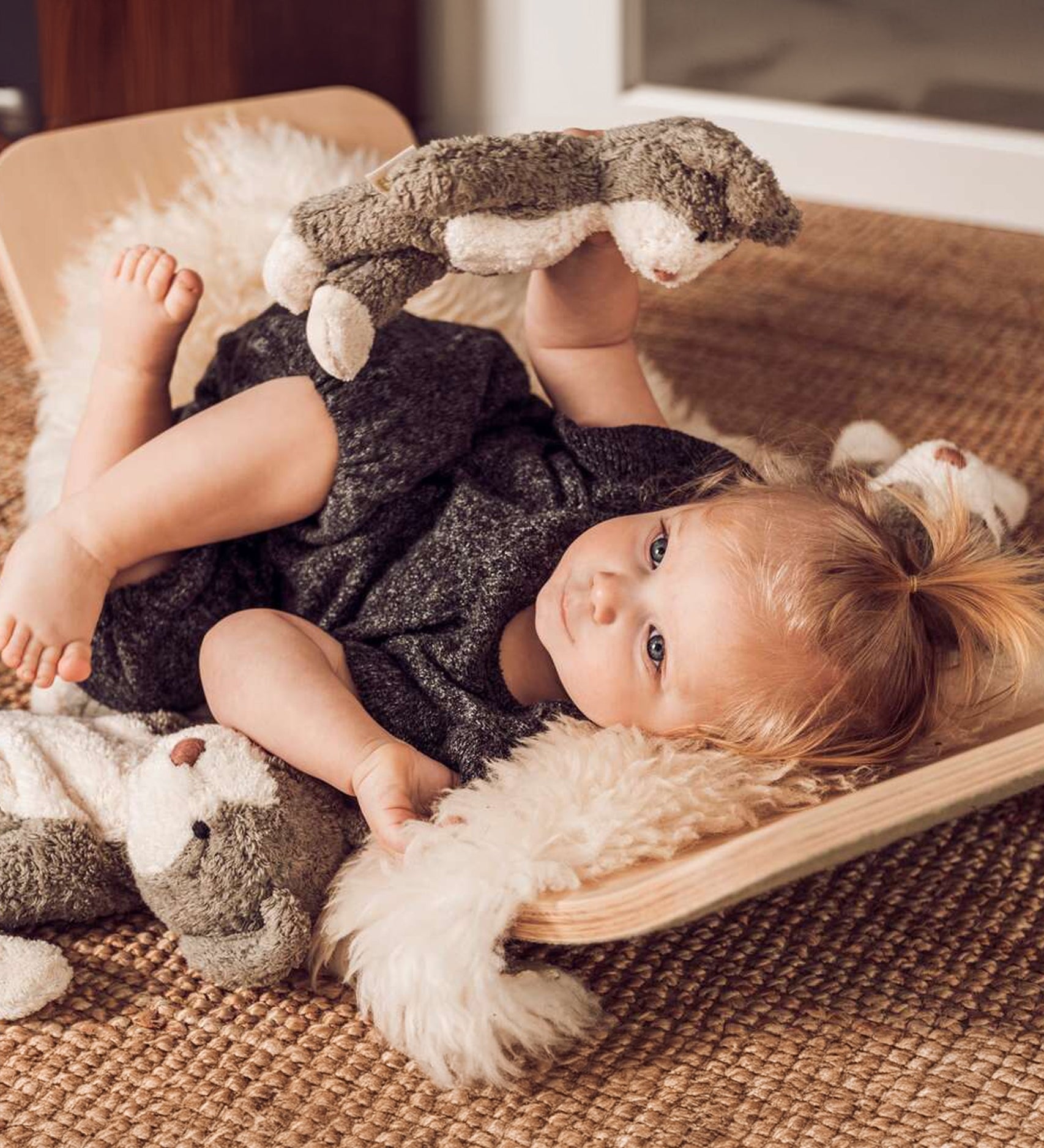 A child laying down in a Wobbel board, playing with a Senger Baby Cat