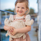 A small child holding the Senger Naturwelt small cuddly crab outdoors. Organic GOTS cotton plush soft toy with natural wool filling and spelt husk heat cushion.