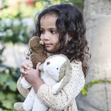 Senger Floppy Dog Small held by child, made from natural materials like organic cotton and sheep's wool.