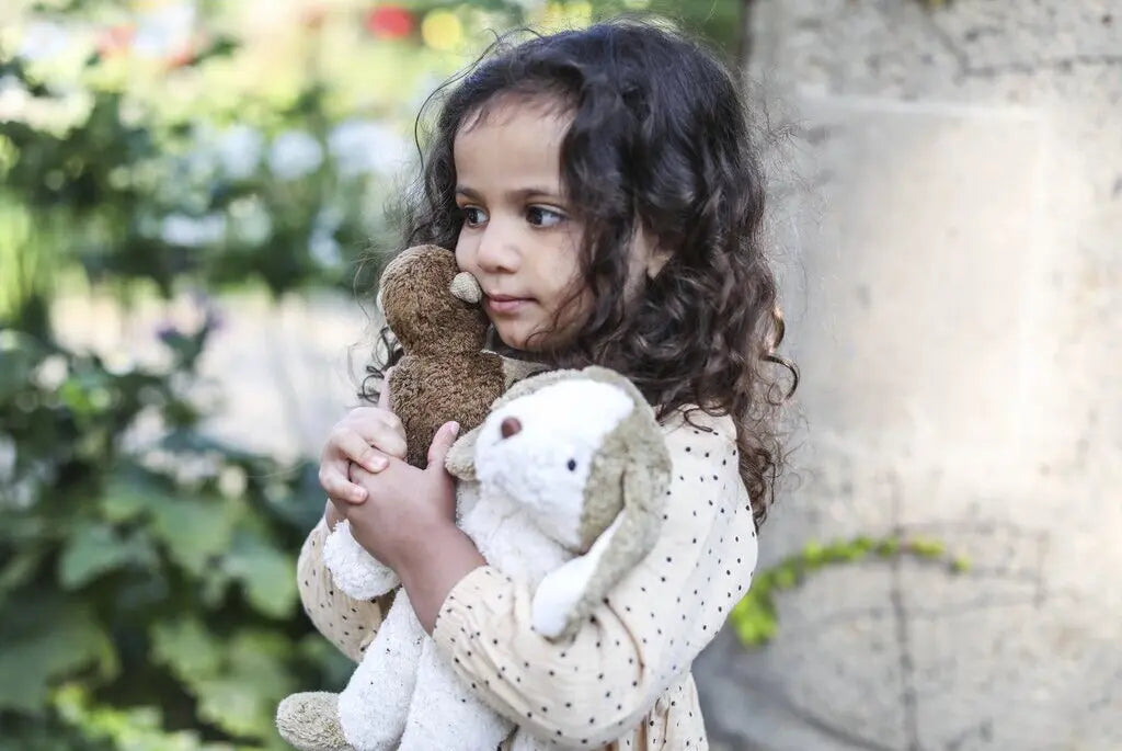 Senger Floppy Dog Small held by child, made from natural materials like organic cotton and sheep's wool.
