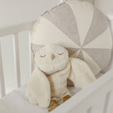 A GOTS organic cotton snowy owl soft toy by Senger available at Babipur sitting upright in a cot showing the cute, sleepy facial features.