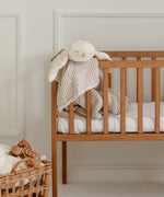 A GOTS organic cotton snowy owl soft toy by Senger available at Babipur hanging over a wooden baby's cot