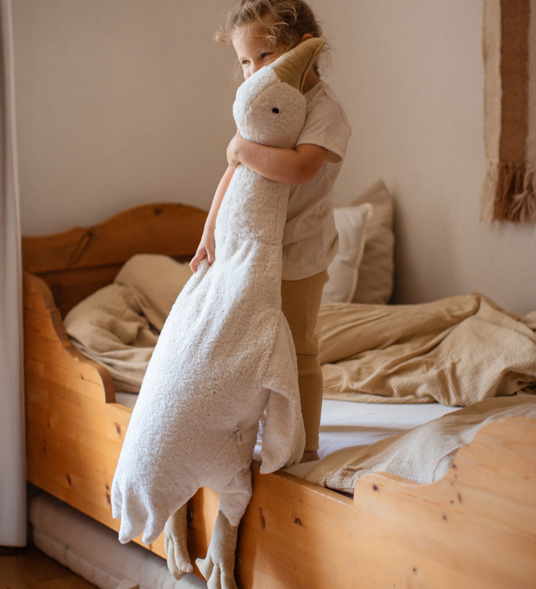 A small child holding the white cuddly Senger XL goose giving an idea of the size of the soft toy