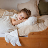 A close up of a small child lying next to the white Senger XL goose. A organic heatable soft toy made from GOTS cotton plush and natural wool.