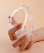 A person pressing on the front of the Haakaa Ladybug Silicone Breast Milk Collector, to show how to attach the pump to the breast