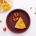 Eco Rascals Silicone Baby Plate in burgundy without divider, with a slice of quiche and tomatoes.  