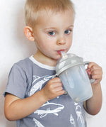 A child using the Haakaa Generation 3 Silicone Bottle Handle with the Haakaa Sippy attachment and bottle