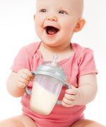 A baby smiling, and holding the Generation 3 Silicone Bottle Handle in their hands