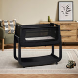 The black graphite wooden SnuzPod5 bedside crib with wheels, that has been wheeled into the living room 