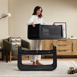 A woman detaching the SnuzPod5 bassinet from the main rocking frame, showing how easily portable this baby cot is.
