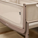 A closeup of the corner of the mocha coloured wooden SnuzPod5 bedside crib, showing where the bassinet can detach from the main rocking frame. 