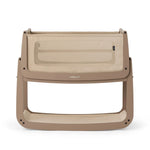 The SnuzPod5 bedside baby crib with a creamy mocha brown coloured wooden frame, beige mesh sides, and a white mattress. 