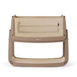 The SnuzPod5 bedside baby crib with a creamy mocha brown coloured wooden frame, beige mesh sides, and a white mattress. 