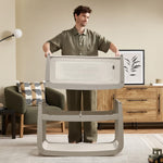 A man detaching the SnuzPod5 bassinet from the main rocking frame, showing how easily portable this baby cot is.