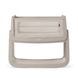 The SnuzPod5 bedside baby crib with a light grey wooden frame, light grey mesh sides, and a white mattress. 